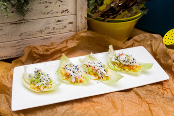 Breadless snacks on iceberg lettuce leaves cucumber slices and diced mango, crabmeat and black sesame seeds