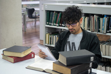 Estudiante con gafas y piercing leyendo y estudiando en la biblioteca