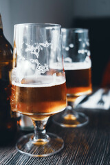 Two large glasses of cold beer. Goblets half full of amber beer with foam. Beer break in a bar with friends. Comfort, alcohol and a passion for good beer.
