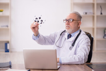 Old male doctor studying molecular model at the hospital