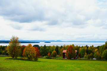 Swedish landscape under a cloudy sky. Wide meadows, autumn weather and blue lakes. Streets and houses near the big lake Siljan. Wide angle photography.