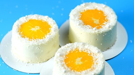 Small cakes with orange and coconut on a blue background.