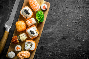 Set of different types of sushi and rolls on wooden cutting Board.