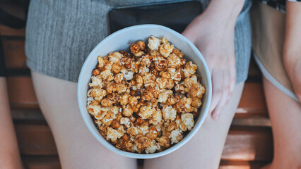 Friends eating popcorn on the street. Close-up of hands.