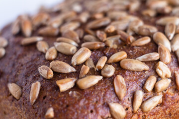closeup of dark baked bread crust sprinkled with sunflower seeds with defocused background