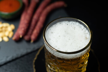 Beer is poured from a can into a glass against the background of sausages