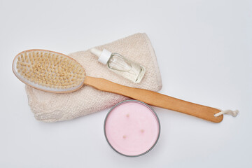 a wooden brush and a white towel next to a pink toothbrush on a white background with copy space in the top right corner