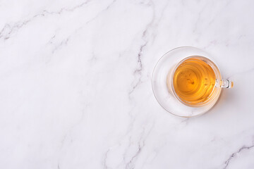 a cup of tea on a white marble surface with copy space in the top right corner, and an overhead image of a glass