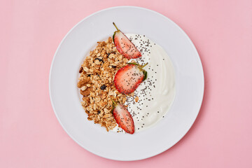 some food on a white plate with strawberries and grano de galloas in the background is a pink wall