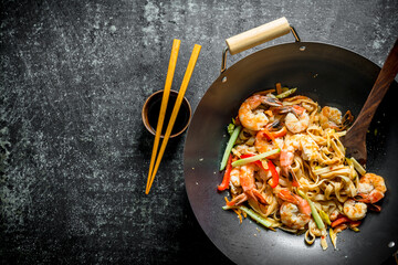 Freshly cooked Asian Udon noodles in a wok pan with soy sauce and chopsticks.