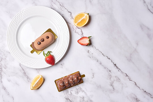 Some Desserts On A White Plate With Lemon Slices And Strawberries In The Photo Is Taken From Above It