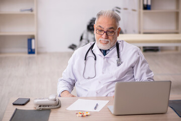 Old male doctor working in the clinic