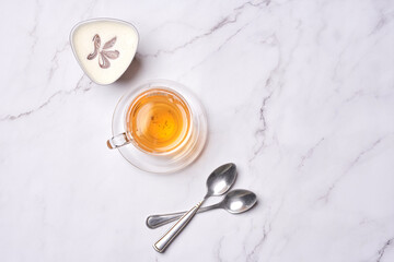 some tea and spoons on a white marble counter top with a butterfly in the image is taken from above