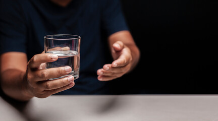 Man's hand holding a glass of clean water and making a gesture inviting clean water.