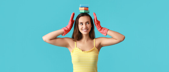Pretty young woman with sponges on light blue background