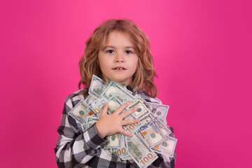 Kid showing money dollar bills, standing dreamy of rich against isolated pink red studio background.