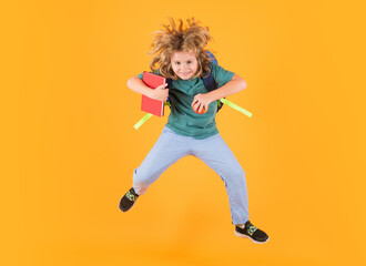 Fototapeta na wymiar Full length of excited kid jumping. School boy in school uniform with backpack jumping on yellow isolated background. Kids learning knowledge and kids education concept.