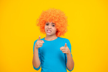 Girls birthday party. Funny kid in curly redhead wig. Time to have fun. Teen girl with orange hair, being a clown. Angry face, upset emotions of teenager girl.