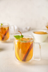 Glass cup of fruit tea with pear, mint and cinnamon on light background, closeup