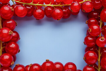 Frame made of red currant on color background, closeup