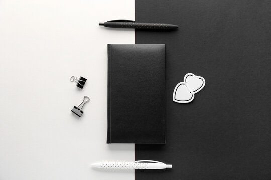 Notebook with pens on black and white background