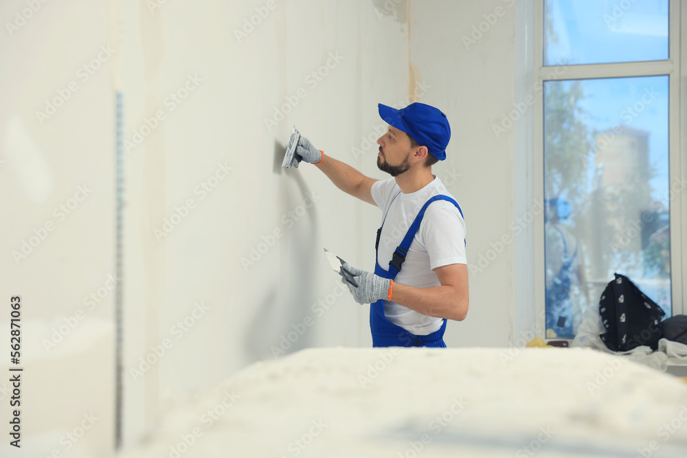 Sticker Professional worker plastering wall with putty knives indoors