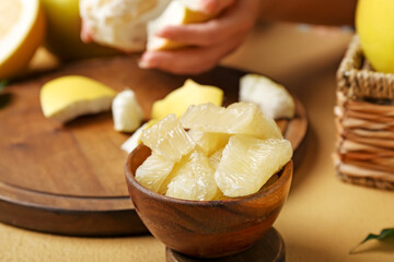 Wooden bowl with slices of tasty pomelo fruit on table, closeup