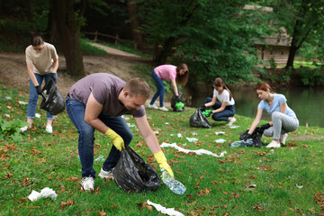 Group of people with plastic bags collecting garbage in park