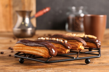 Grid with tasty chocolate eclairs on wooden table