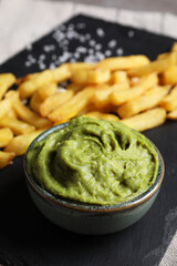French fries and avocado dip on serving board, closeup