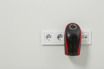 Compact electric heater charging from socket indoors, space for text
