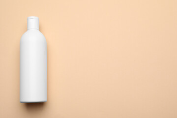 Bottle of shampoo on beige background, top view. Space for text