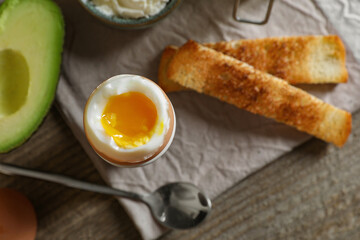 Soft boiled egg served for breakfast on wooden table, flat lay