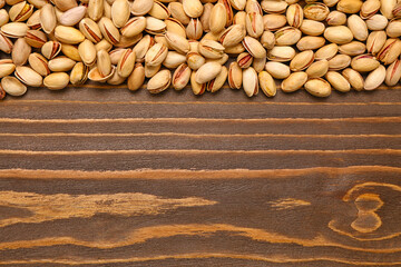 Heap of tasty pistachio nuts on wooden background
