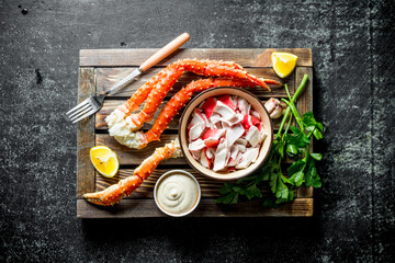 Crab meat and fresh crab on a wooden tray with lemon slices, sauce and herbs.