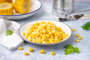 Plate with canned corn kernels, parsley leaves and napkin on grey table