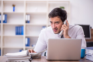 Young male employee unhappy with excessive work at workplace