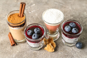 Shots of various pudding with blueberry, cinnamon and cookie pieces on grey table
