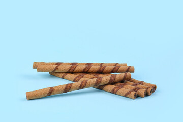 Tasty wafer rolls with chocolate on blue background