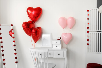 Table with engagement ring and balloons for Valentine's Day in light room