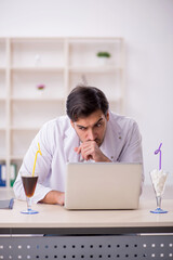 Young male chemist examining soft drink