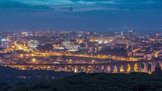 Panoramic dawn view over Lisbon and Almada from a viewpoint in Monsanto night to day transition timelapse. Aerial top overview with traffic and Aqueduct of the Free Waters