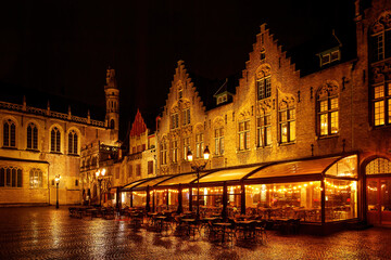 Fototapeta premium Restaurant with a terrace in the old Europe town square on a rainy night.