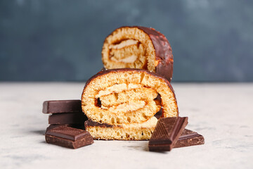 Pieces of tasty sponge cake roll and chocolate on grunge background