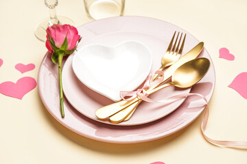 Table setting for Valentine's Day with rose and hearts on light background