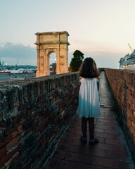 little girl walking on the fortified walls near to Trajan's arch in Ancona