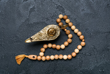 Aladdin lamp of wishes and prayer beads for Ramadan on dark background