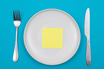 Colored Sticky Note or Memo Paper on White Ceramic Plate Lying On Blue Background - Top View, Flat Lay