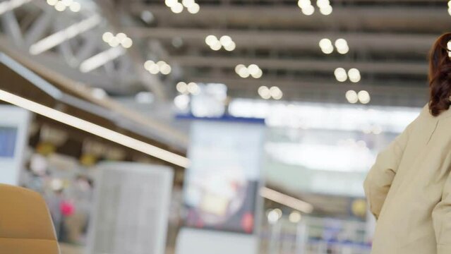 Asian woman waiting for departure at the airport on vacation holiday. Asia female passenger using mobile smart phone and sitting in terminal hall while waiting for her flight