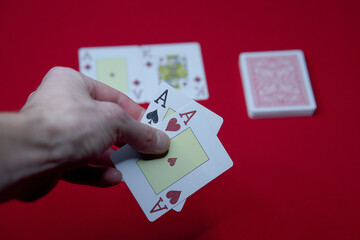 player shows two play card aces on a red table in a casino. gambling